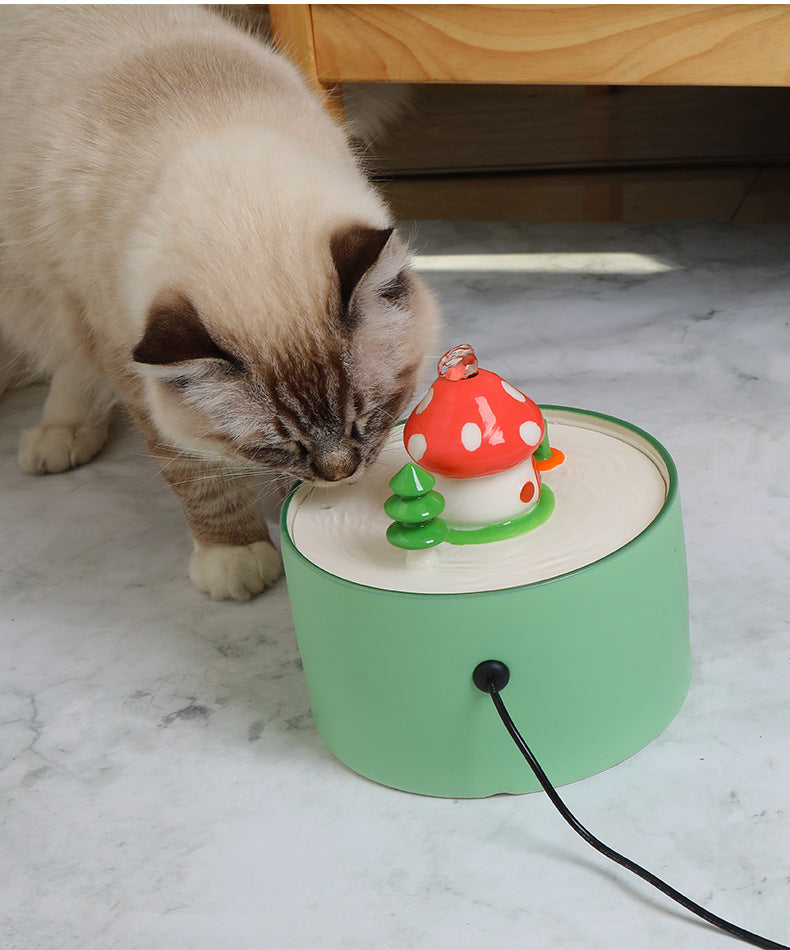 Cat drinking from green automatic pet water dispenser with red mushroom design on top