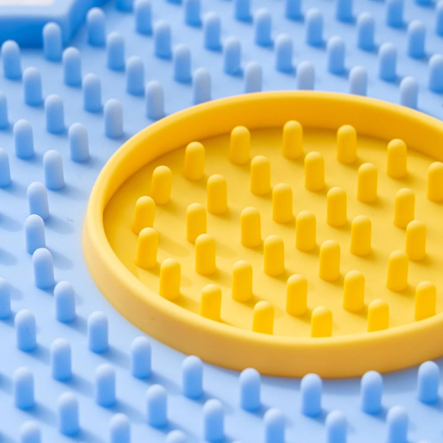 Close-up of Cats Lick Pad With Suctions in yellow and blue for pet grooming and comfort