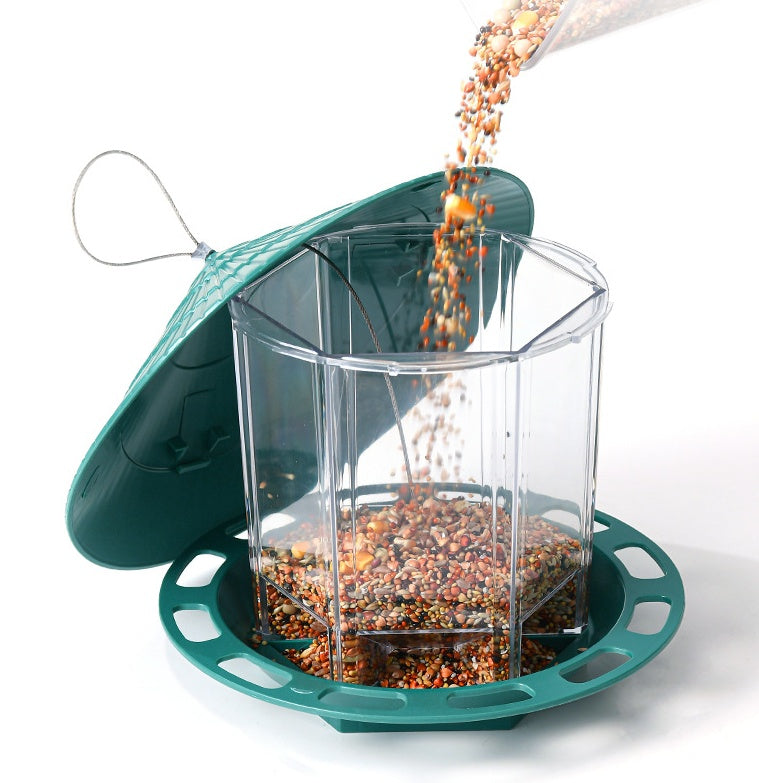 Transparent Bird Feeder with green base and lid being filled with mixed bird seed