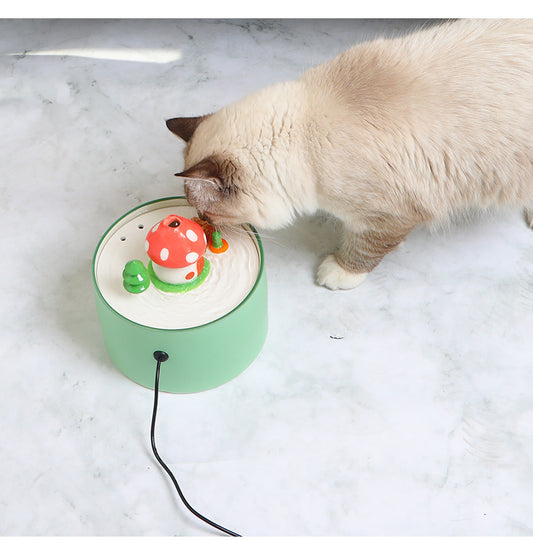 Cat drinking water from a green automatic pet water dispenser with mushroom design