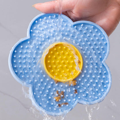 Blue and yellow Cats Lick Pad With Suctions shaped like a flower with water pouring over it for easy cleaning
