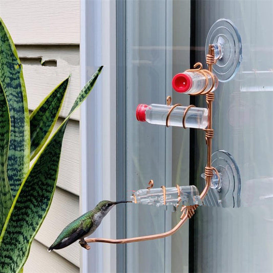 Copper Garden Bird Feeder with multiple feeding tubes attached to a glass window with suction cups